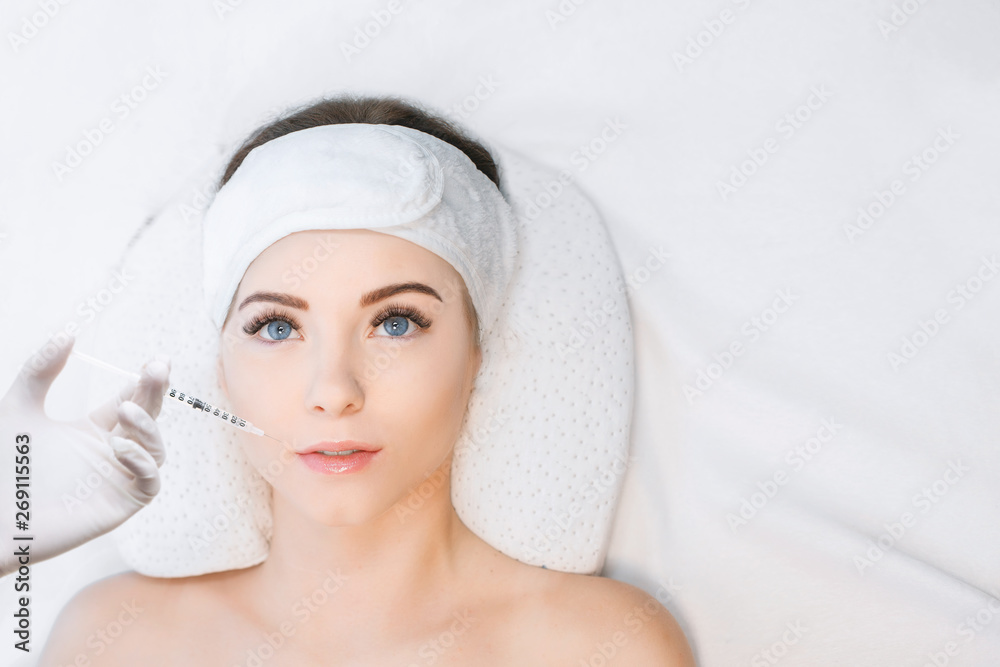 Woman receiving injections in the lips zone lying on the medical couch. Close up of hands of cosmetologist making injection in female lip. Plastic surgery concept. Woman receiving injections in the lips zone lying on the medical couch. Close up of hands of cosmetologist making injection in female lip. Plastic surgery concept.