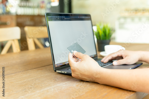 Businessman online working hand holding credit card and using laptop in cafe.