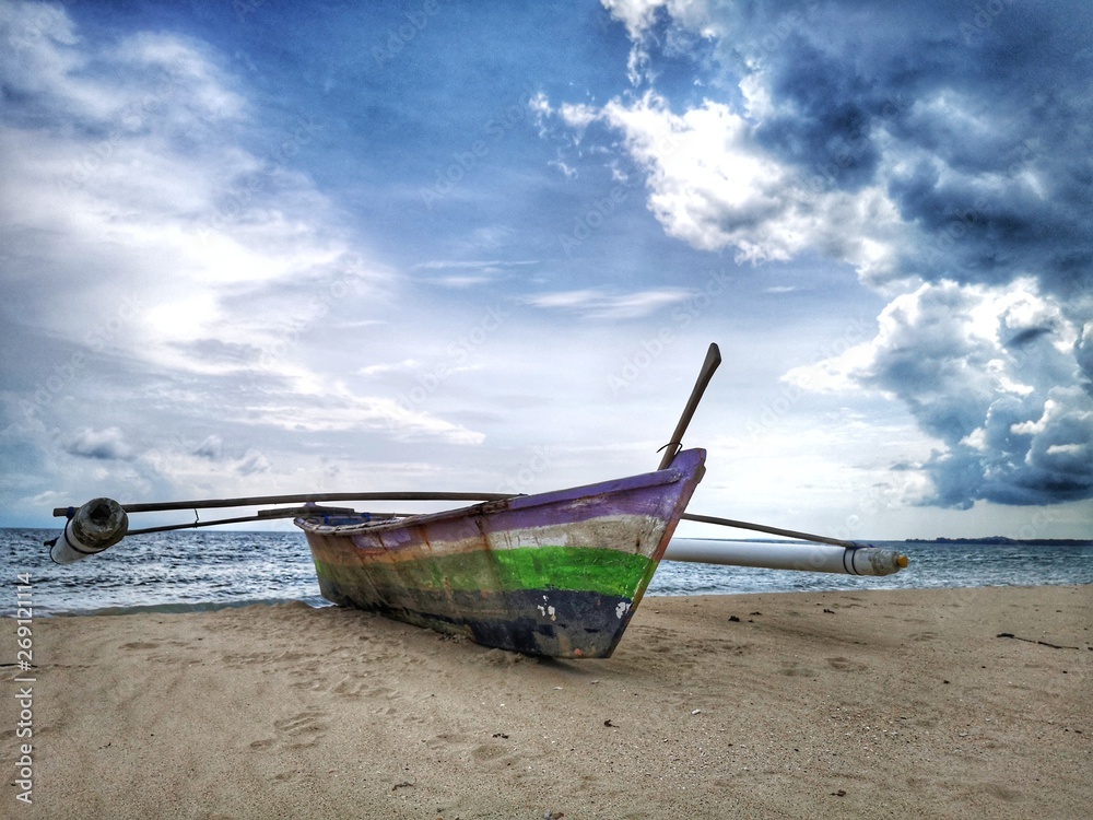 A traditional fishing canoe on the beach during the low tide.