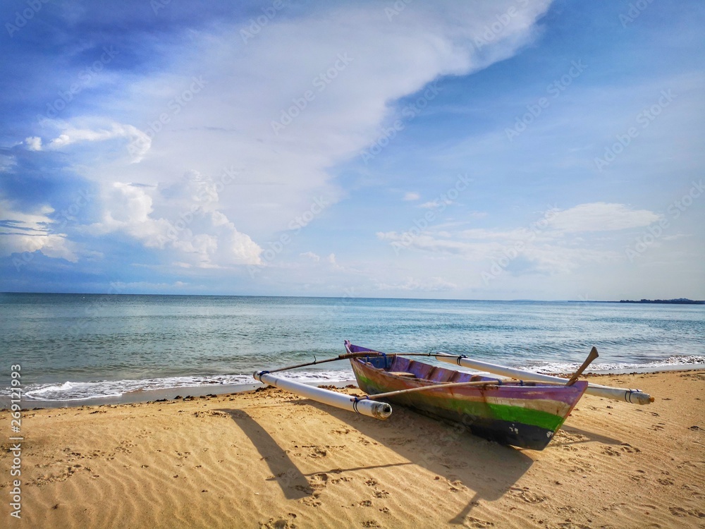 A small traditional fishing canoe on the beach during the low tide. A small traditional fishing canoe on the beach during the low tide.