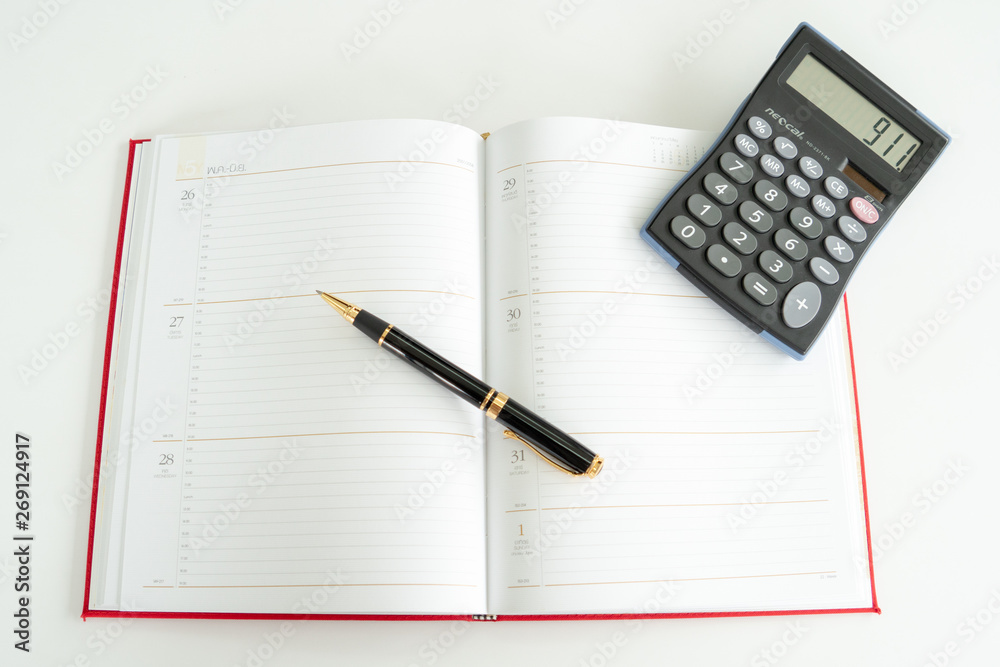 Daily plan book spread out with a fountain pen and calculator on it. Daily plan book spread out with a fountain pen and calculator on it.