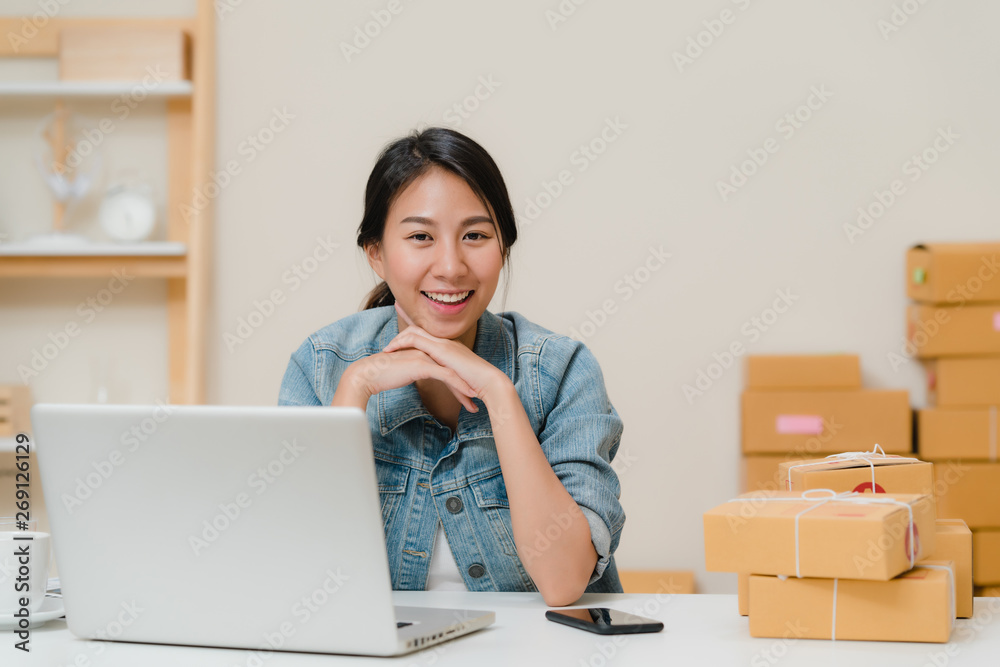 Business woman feeling happy smiling and looking to camera while working in her office at home. Beautiful Asian young entrepreneur owner of SME with small business owner at home office concept. Business woman feeling happy smiling and looking to camera while working in her office at home. Beautiful Asian young entrepreneur owner of SME with small business owner at home office concept.