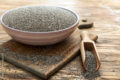 Scoop and bowl with chia seeds on wooden table