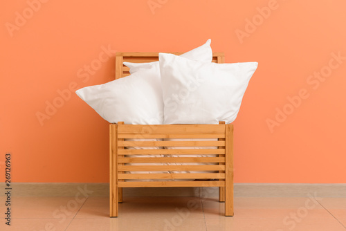 Fototapeta Naklejka Na Ścianę i Meble -  Soft pillows in wooden box against color wall