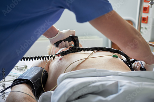 Doctor intensivist performs defibrillation to critical patient photo