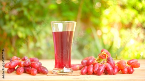 Fresh red grape juice and grapes on wooden garden table, refreshing organic antioxidant beverage 