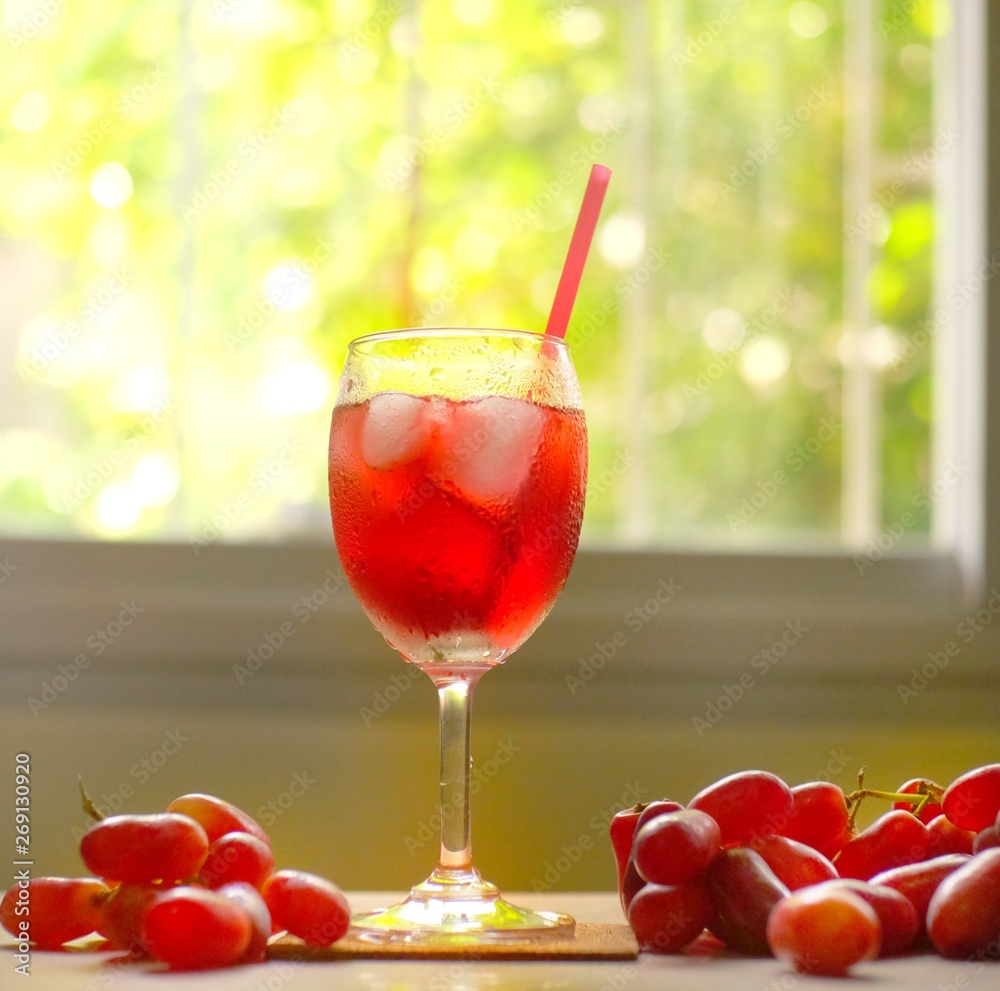 Fresh red grape juice and grapes on wooden garden table, refreshing organic antioxidant beverage Fresh red grape juice and grapes on wooden garden table, refreshing organic antioxidant beverage