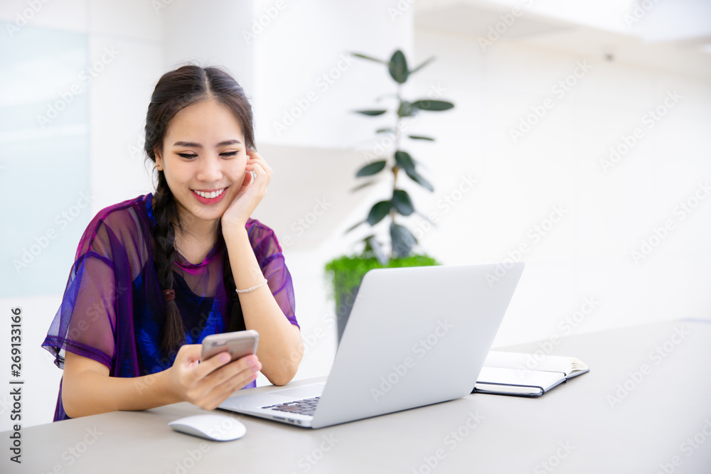 Young business female using smart phone while working on computer laptop. Young business female using smart phone while working on computer laptop.