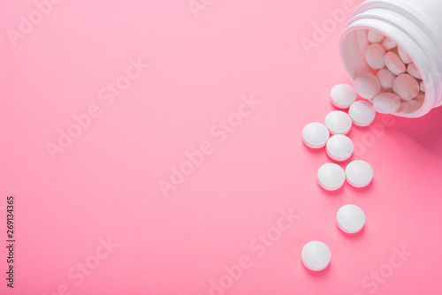 Closeup of white pills on a pastel pink color background