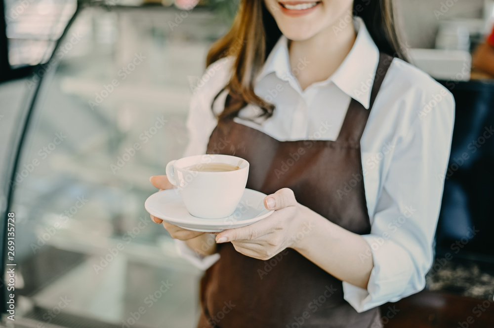 Barista woman serving coffee cup at cafe, Asian female barista holding coffee served with smiling face.