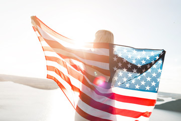 Patriotic holiday. Young woman holding USA flag.