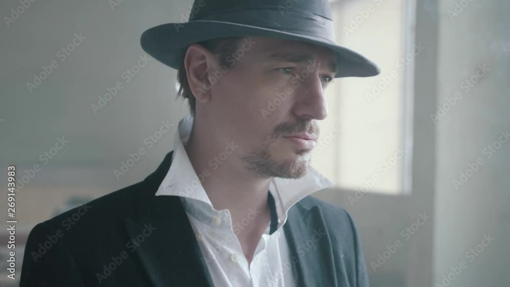 Portrait handsome confident man in a hat smoking cigar in an abandoned building. The head of the mafia is in an empty building. Criminal authority portrait, close up. Portrait handsome confident man in a hat smoking cigar in an abandoned building. The head of the mafia is in an empty building. Criminal authority portrait, close up.