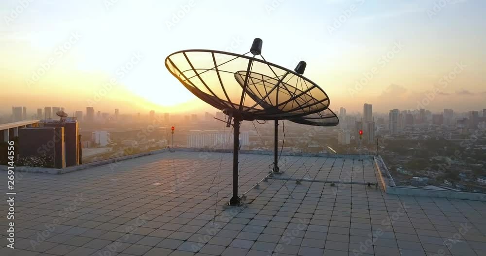 sunset in Bangkok, Thailand, appearing over antennas on a rooftop with a panorama sunset in Bangkok, Thailand, appearing over antennas on a rooftop with a panorama
