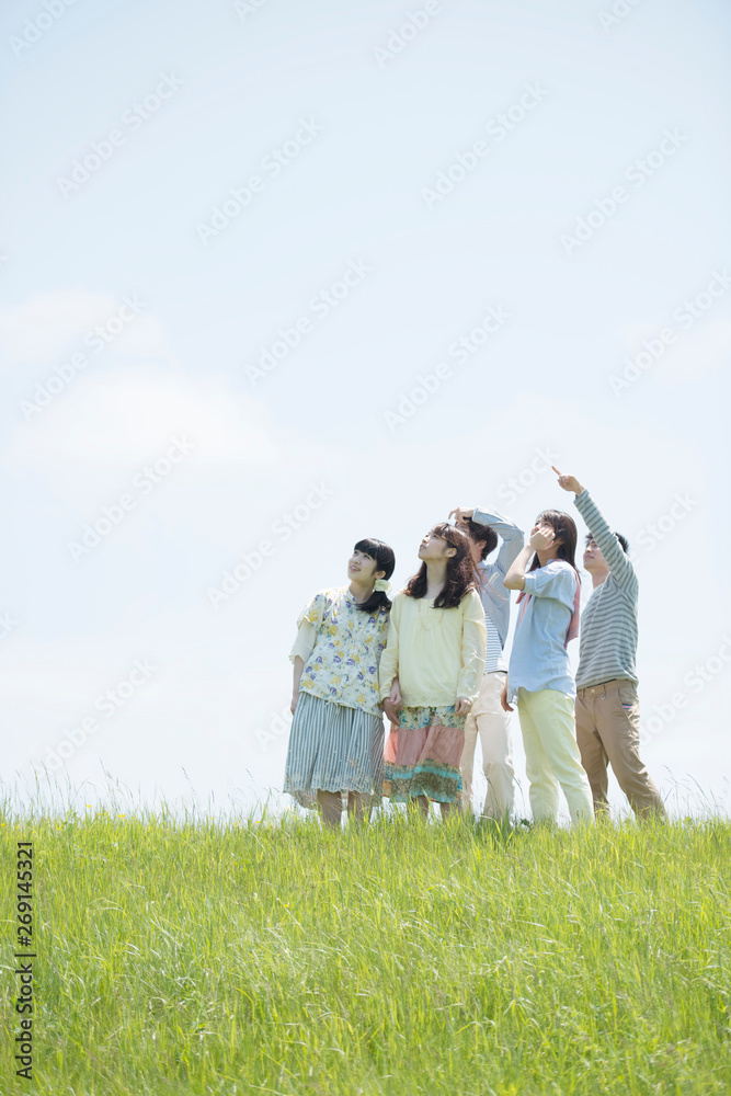 草原で空を見上げる大学生