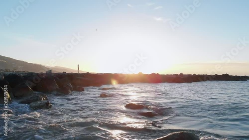 seagull flying over sea rocks during sunrise photo