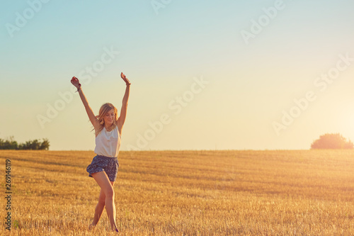 Young woman jumping and running in a wheat field.
