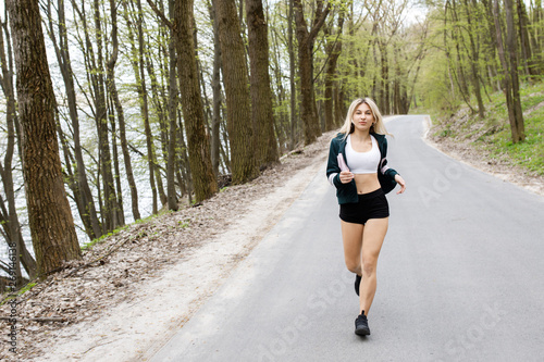 A young, pretty girl blonde is training before running outdoors. Sports activity. Exercise Outdoors. Health and benefits for the body