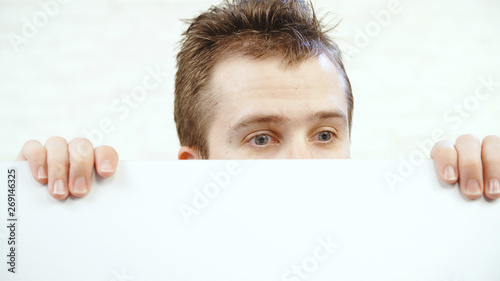 Billede på lærred Male person peeping over the white wall