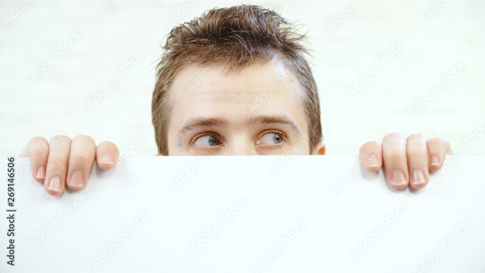Man scared hiding behind the white wall Man scared hiding behind the white wall