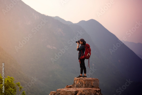 Backpacker woman take photo on peak mountain