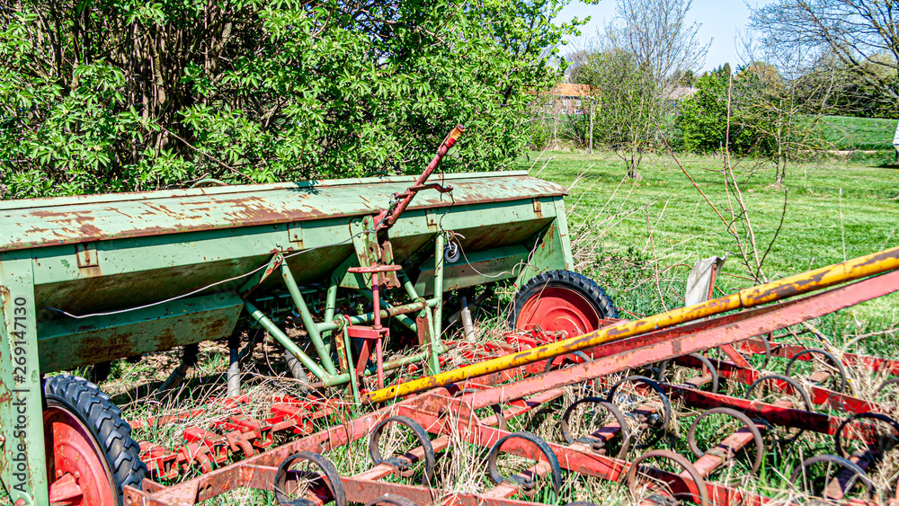 Old, rusted and abandoned farming machinery on a fruit farm, kongskilde triland grower, sunny spring day in the countryside in Oensel south Limburg in the Netherlands Holland
