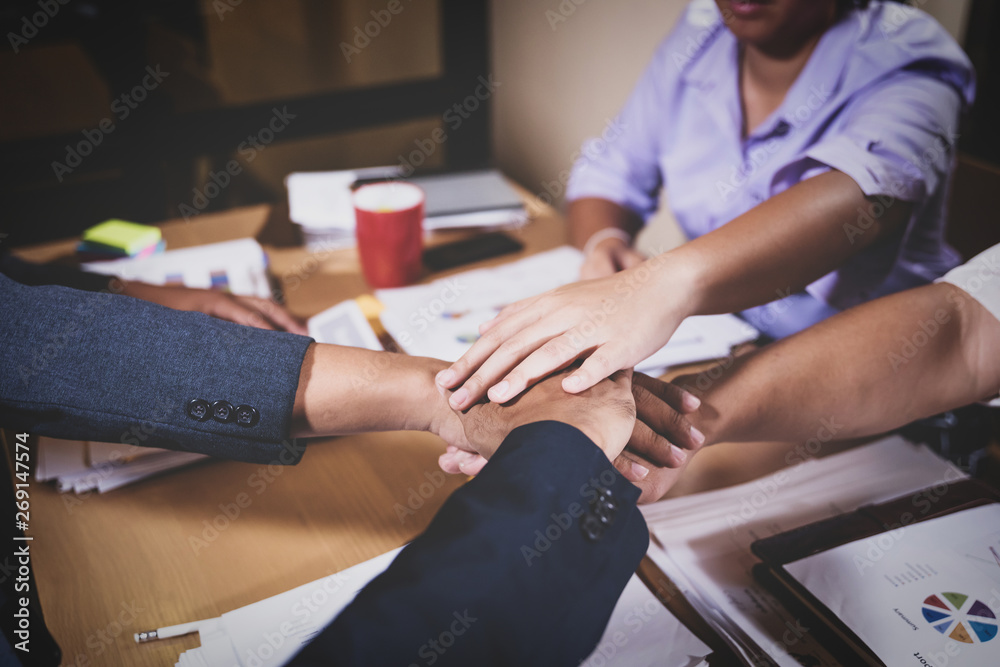 Obraz premium teamwork colleagues putting hands together across meeting table