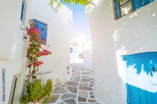 Street with beautiful pink bougainvillea flowers and white house walls. Colourful Greek street in Lefkes, Paros island
