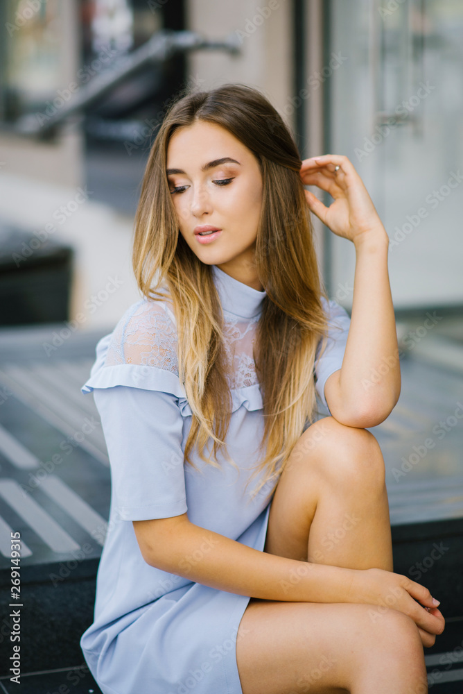 A young beautiful girl in a blue dress with a beautiful make-up has closed her eyes, sits and thinks about something pleasant and happy. The concept of peace and tranquility
