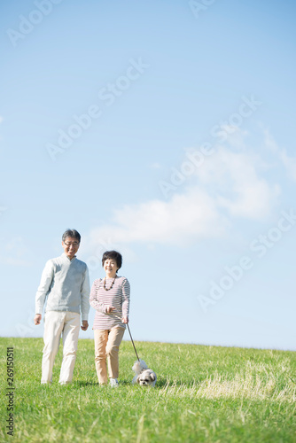 草原で犬の散歩をするシニア夫婦