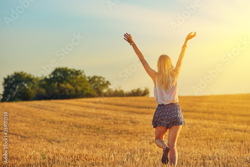 Cute young woman jumping in a wheat field.