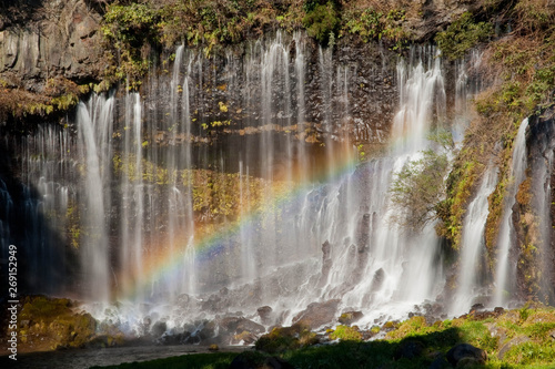 糸のような水の流れのある滝と虹