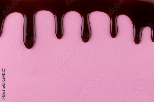 Abstract background with cake topping real chocolate flowing down on pink background - space for text