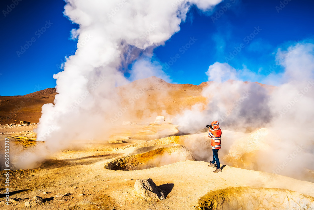 Fototapeta premium Photographer among sunshine huge steaming geysers area in Bolivia