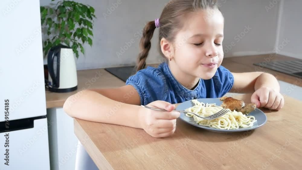 Pretty little girl eats her spagetti pasta dinner with appetite in the kitchen Pretty little girl eats her spagetti pasta dinner with appetite in the kitchen