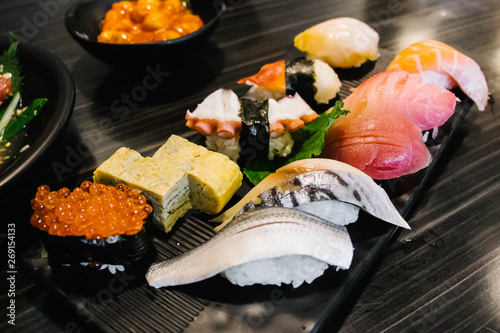 Various types of sushi in black square plate.