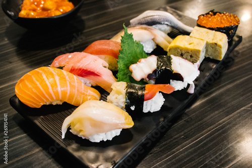 Various types of sushi in black square plate.
