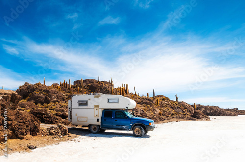 Trip car on the background of rocky sunshine Cactus island, Salar de Uyuni