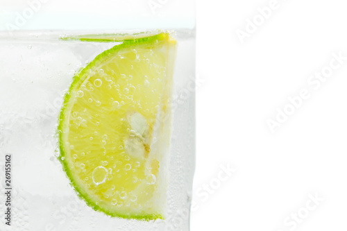 Close up slice of lime in glass sprakling water isolated. photo