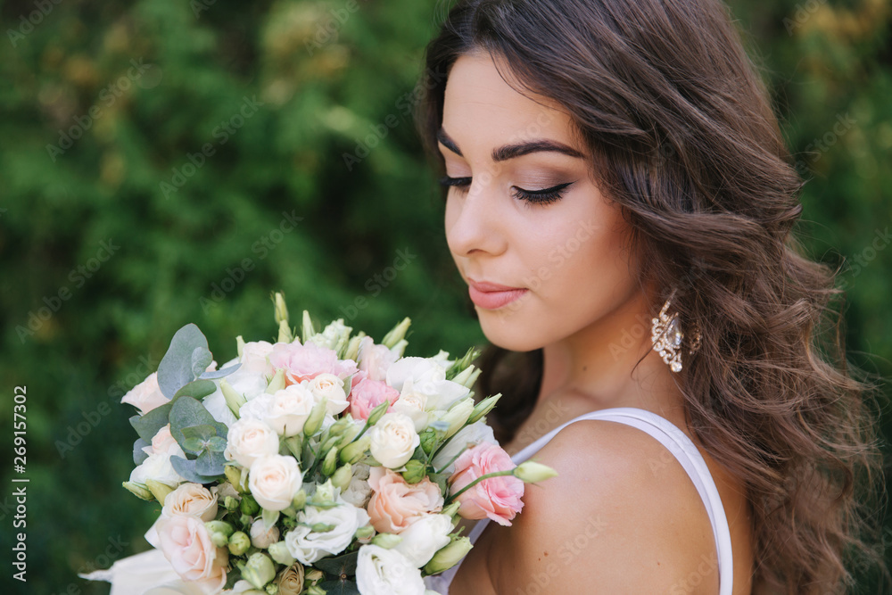 Gorgeous female in white dress slime. Beautiful girl hold a bouquet of flowers in hands Gorgeous female in white dress slime. Beautiful girl hold a bouquet of flowers in hands