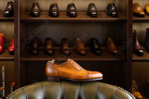 Brown full grain leather shoe in front of wooden display in men shoes boutique store. photo