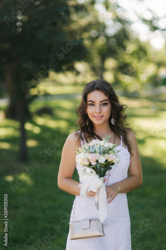 Portrait of yound girl with bouquet. Charming lady in sunny summer day. Stylish woman
