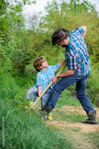 father and son planting family tree. rich natural soil. Eco farm. Ranch. small boy child help father in farming. new life. soils and fertilizers. happy earth day. Dig grounf with shovel. Little plant
