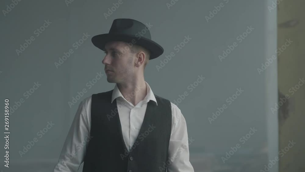 Portrait handsome confident man in a hat looking to the camera in an abandoned building. Boss of the mafia is in an empty building. Criminal authority portrait. Self-confident businessman relaxing. Portrait handsome confident man in a hat looking to the camera in an abandoned building. Boss of the mafia is in an empty building. Criminal authority portrait. Self-confident businessman relaxing.