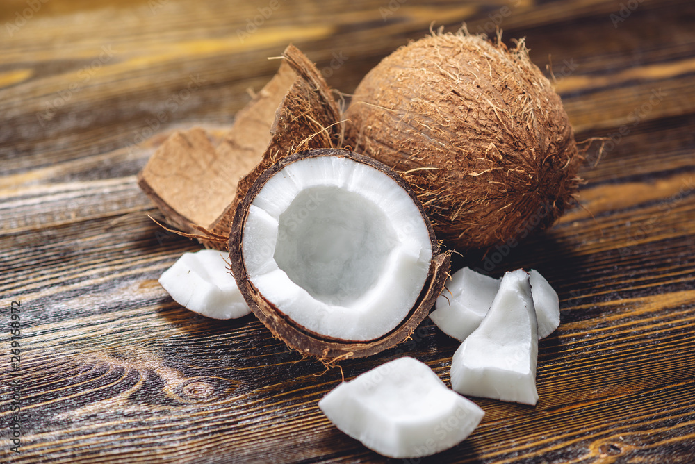 Open coconut with white pulp on wooden background. Organic healthy vegan product widely used in cosmetics Open coconut with white pulp on wooden background. Organic healthy vegan product widely used in cosmetics