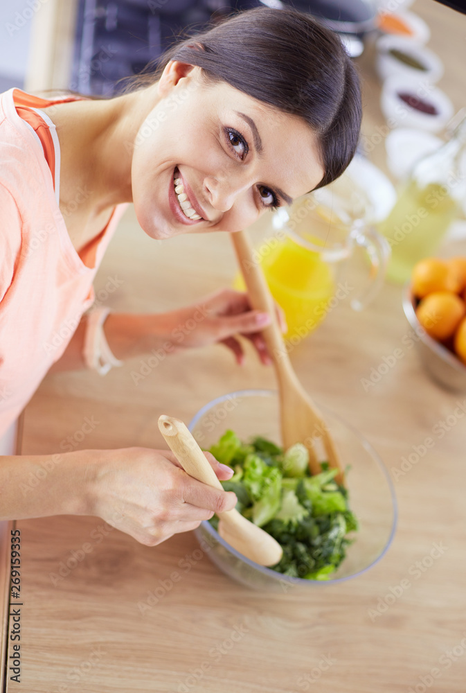 Smiling young woman mixing fresh salad in the kitchen. Smiling young woman mixing fresh salad in the kitchen.