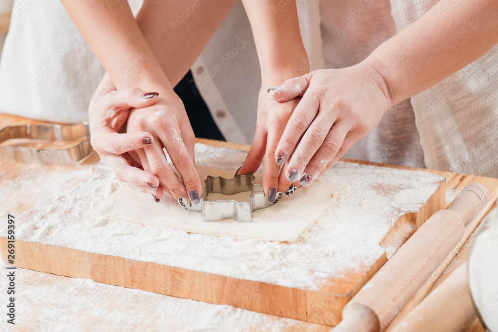 Family leisure in kitchen. Mother teaching daughter how to make cookies from dough. Culinary class. Family leisure in kitchen. Mother teaching daughter how to make cookies from dough. Culinary class.