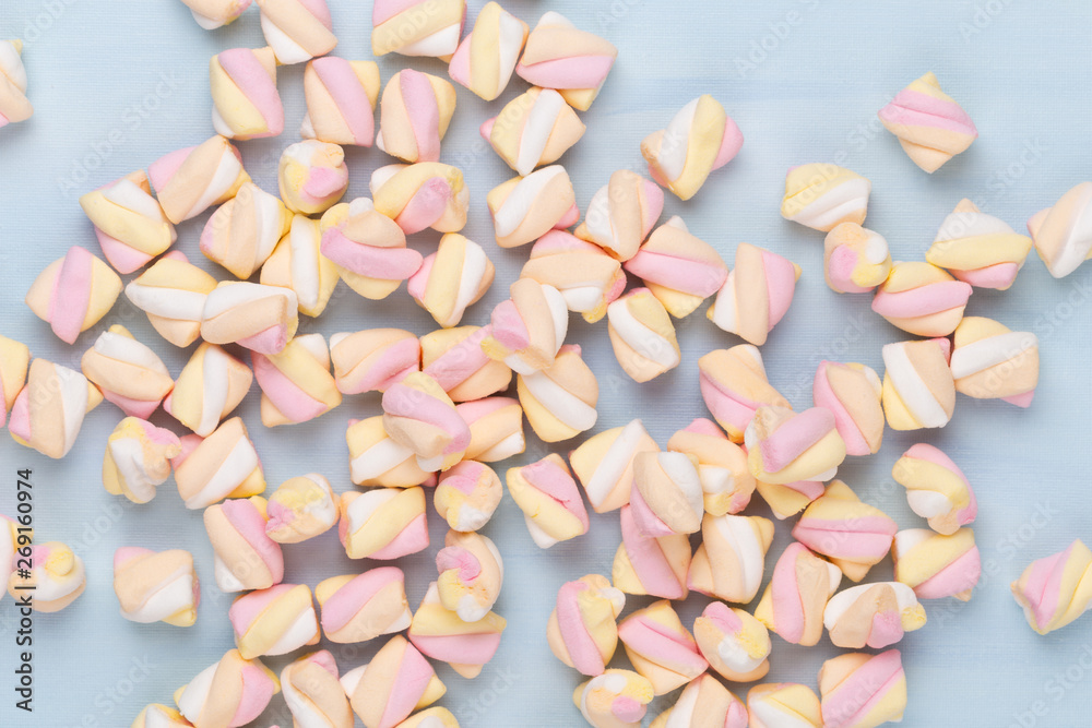 Marshmallows on blue background with copyspace. Flat lay or top view. Background or texture of colorful mini marshmallows. Marshmallows on blue background with copyspace. Flat lay or top view. Background or texture of colorful mini marshmallows.