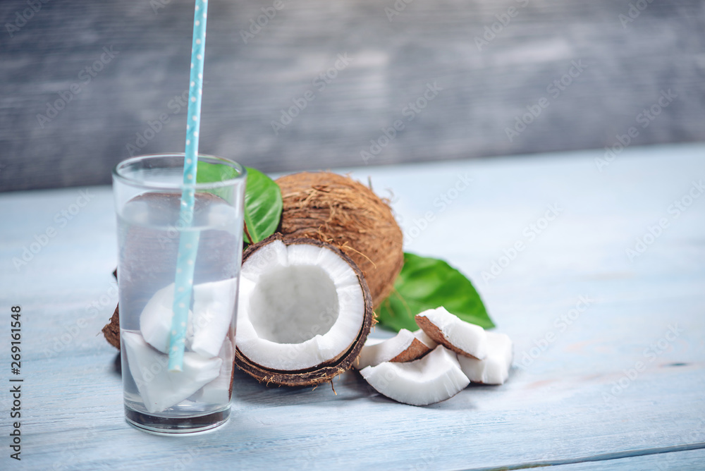 Coconut water in the composition with white flesh on blue wooden background. Organic product widely used in cosmetology Coconut water in the composition with white flesh on blue wooden background. Organic product widely used in cosmetology