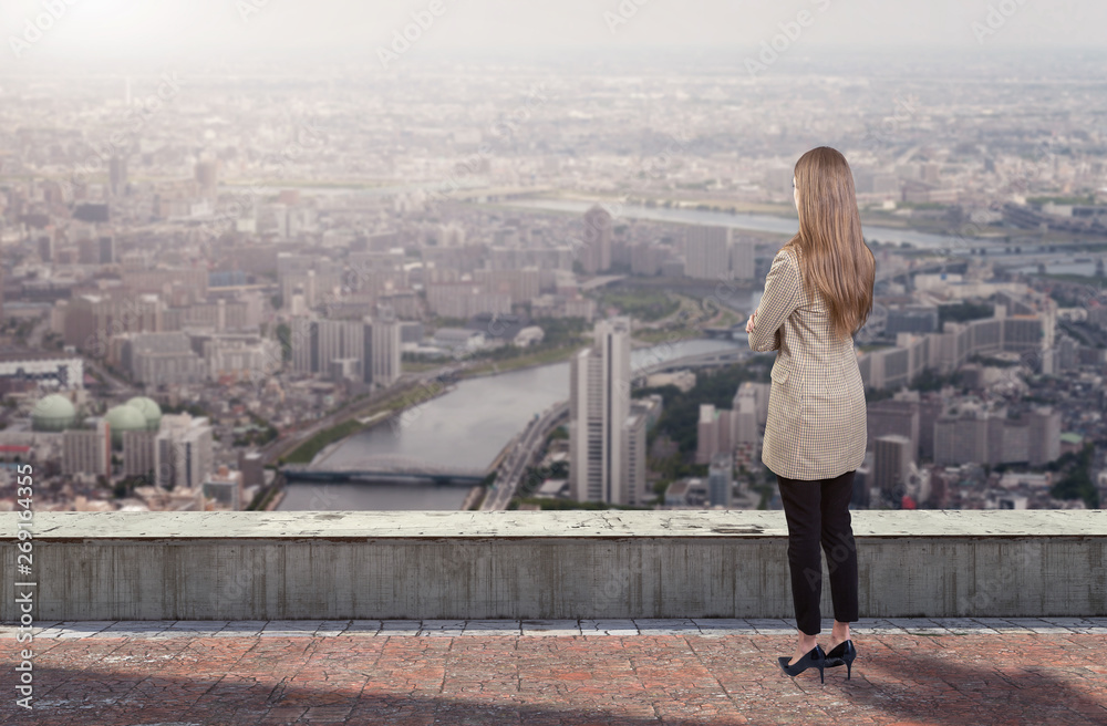 A businesswoman standing on roof looking at city A businesswoman standing on roof looking at city