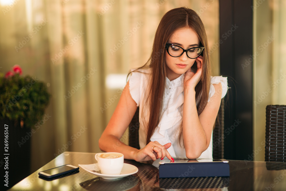 Business lady uses a tablet to work. Beautiful female working in the cafe Business lady uses a tablet to work. Beautiful female working in the cafe